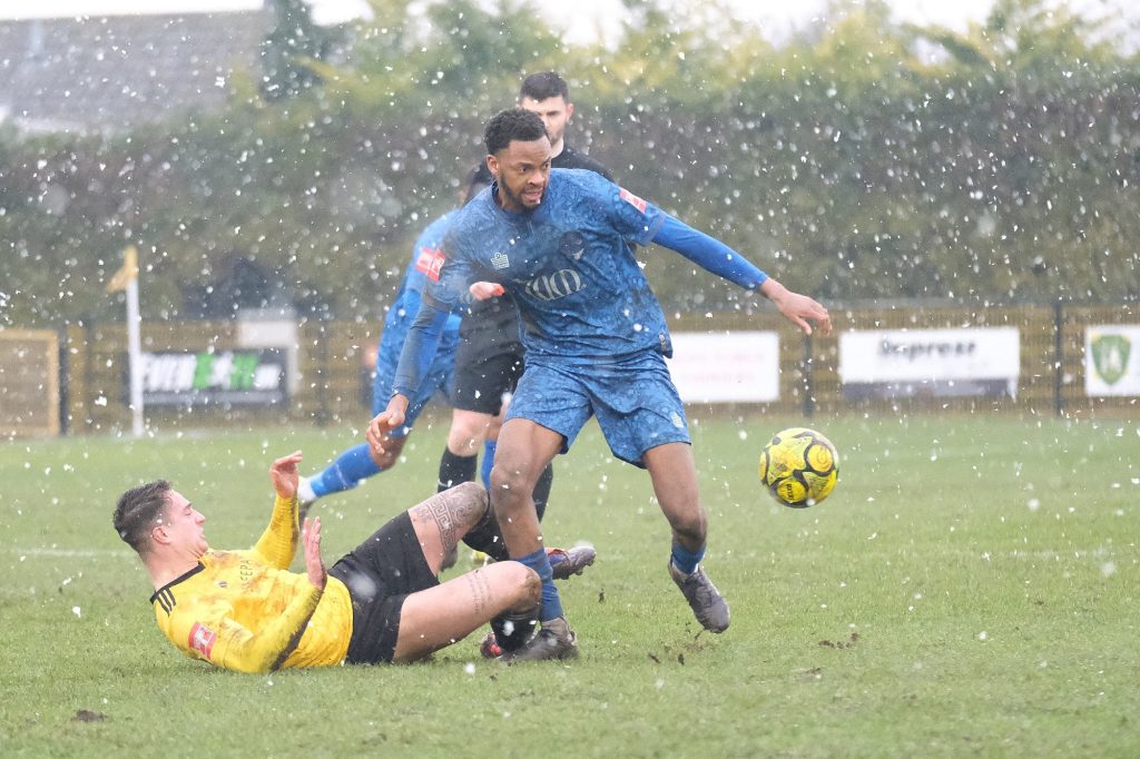 walthamstow's rasheed salau holds off a mildenhall defender